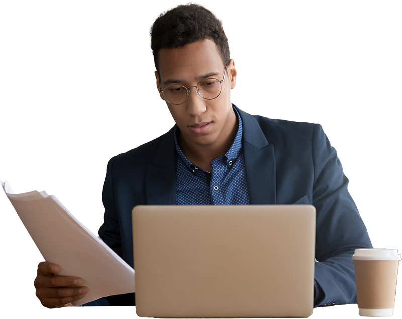 Man working on a laptop while looking at paper documents